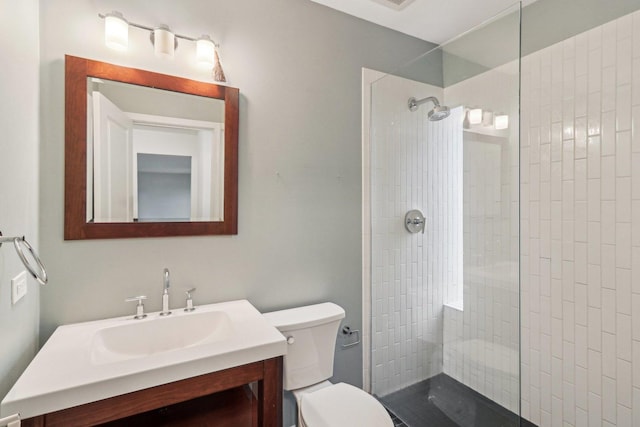 bathroom with vanity, a tile shower, and toilet