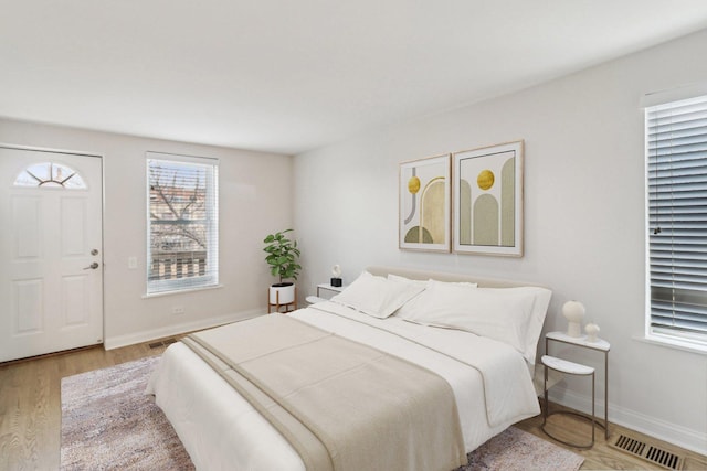 bedroom with baseboards, wood finished floors, and visible vents