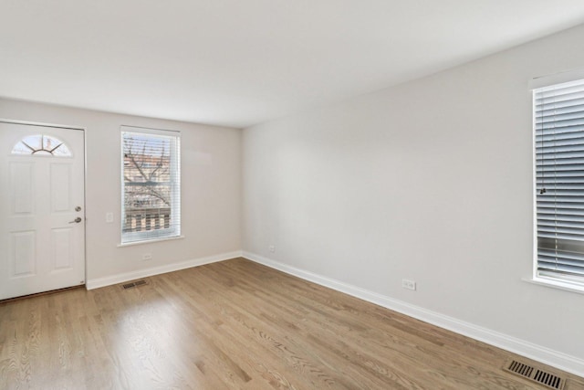 foyer with light wood-style floors, baseboards, and visible vents