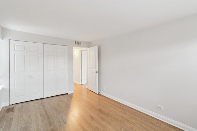 unfurnished bedroom with light wood-style floors, baseboards, a closet, and visible vents