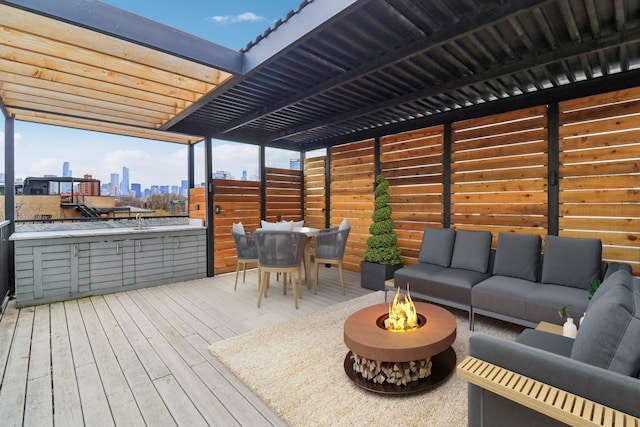 deck with a city view, outdoor dining space, and an outdoor living space with a fire pit
