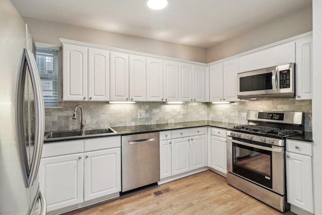 kitchen with a sink, tasteful backsplash, dark countertops, and stainless steel appliances
