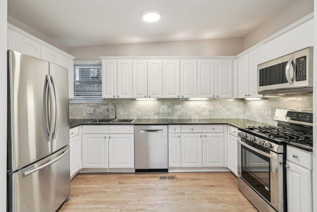 kitchen featuring a sink, dark countertops, stainless steel appliances, and white cabinetry