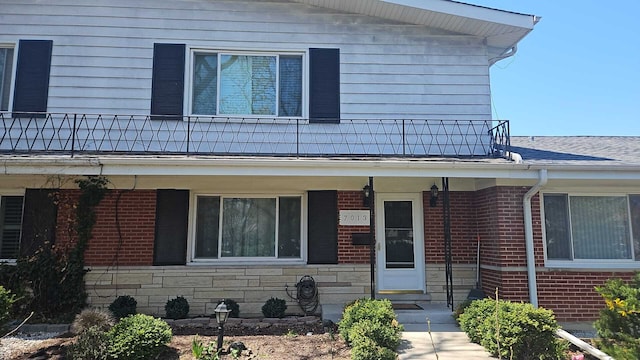 7013 W Greenleaf Ave, Niles, IL 60714 - view of front of house with stone siding, brick siding, and a balcony