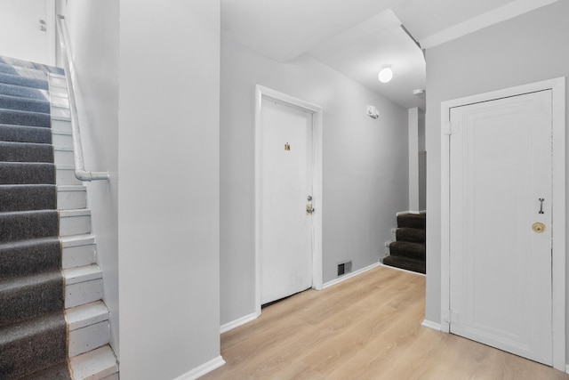 entryway featuring stairway, light wood-style flooring, baseboards, and visible vents