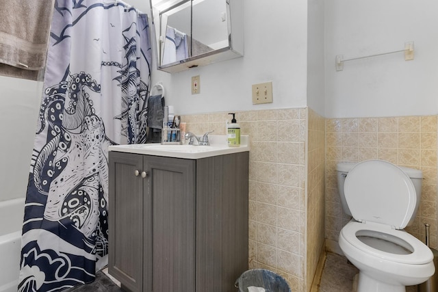 bathroom featuring tile walls, toilet, vanity, and a wainscoted wall