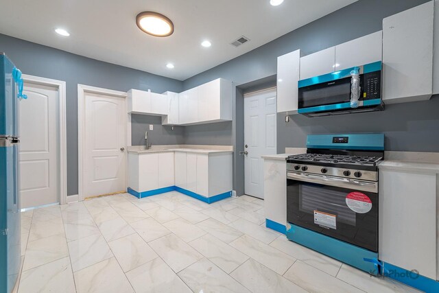 kitchen featuring visible vents, marble finish floor, stainless steel gas stove, light countertops, and white cabinets