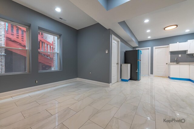 unfurnished living room with a sink, marble finish floor, recessed lighting, baseboards, and visible vents