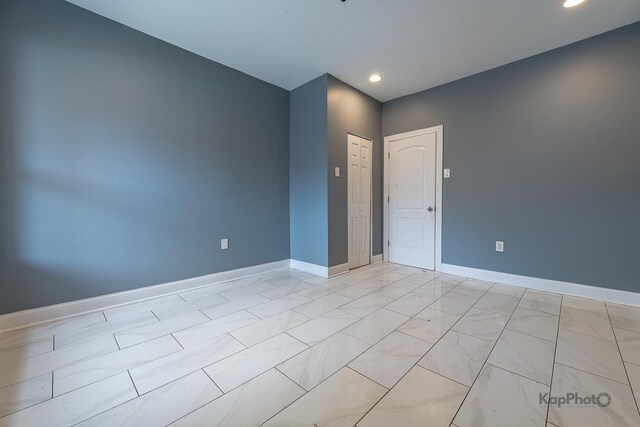spare room with recessed lighting and baseboards