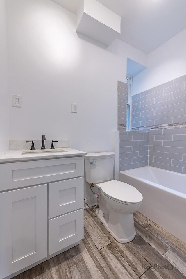 bathroom featuring vanity, wood finished floors, a shower, toilet, and a bathtub