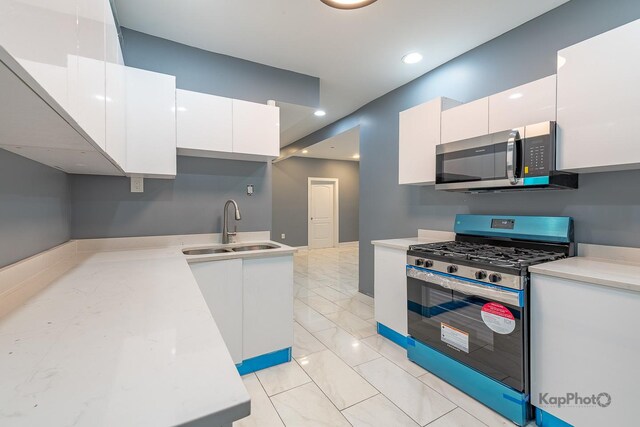kitchen featuring a sink, appliances with stainless steel finishes, white cabinets, and light countertops