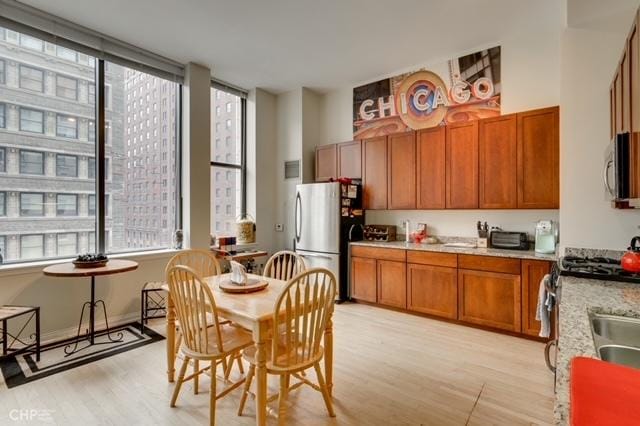 kitchen featuring light countertops, light wood finished floors, appliances with stainless steel finishes, and a healthy amount of sunlight
