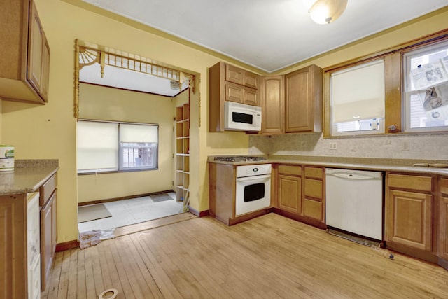 kitchen featuring light wood-type flooring, light countertops, a wealth of natural light, and white appliances