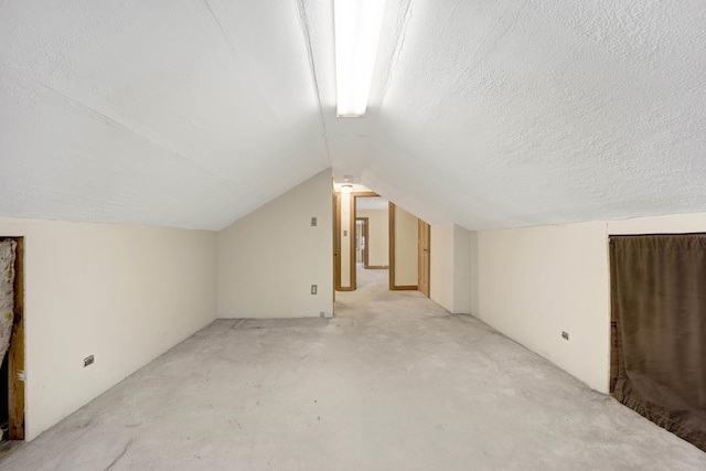 additional living space featuring a textured ceiling and vaulted ceiling