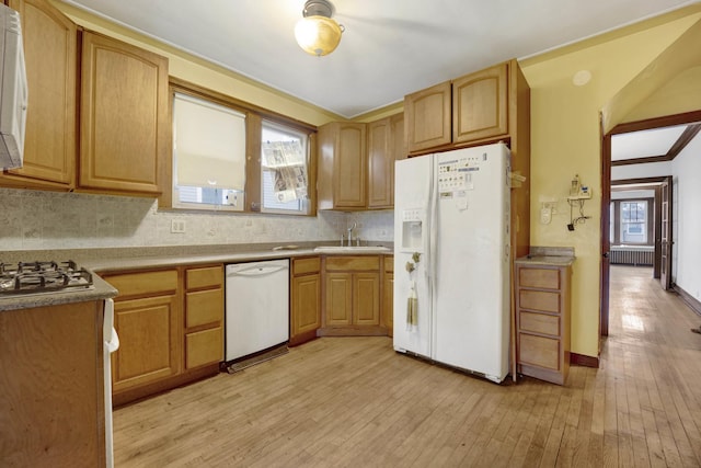 kitchen with radiator heating unit, backsplash, a sink, light wood-style floors, and white appliances