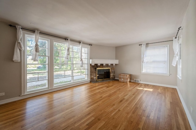 1578 Mccraren Rd, Highland Park, IL 60035 - unfurnished living room featuring wood finished floors, baseboards, a stone fireplace, and plenty of natural light