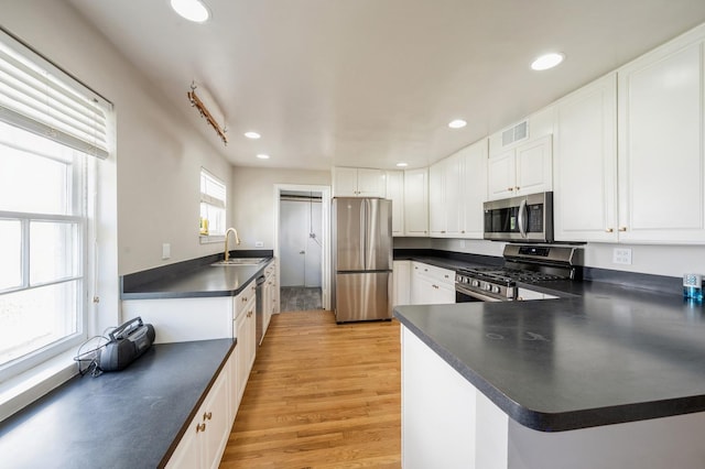 1578 Mccraren Rd, Highland Park, IL 60035 - kitchen with stainless steel appliances, dark countertops, light wood-type flooring, recessed lighting, and white cabinetry