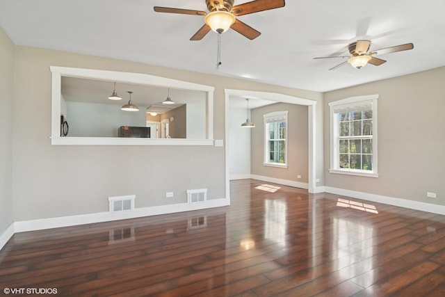 spare room with baseboards, a ceiling fan, wood finished floors, and visible vents