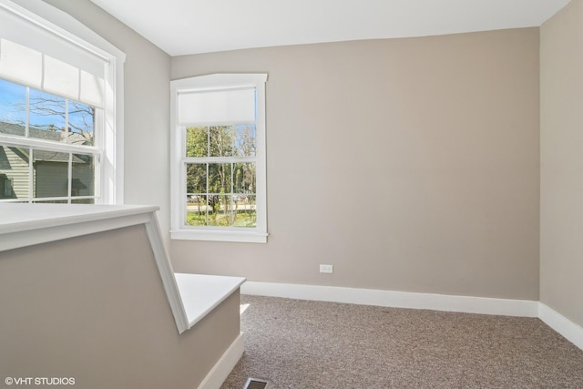 empty room featuring a healthy amount of sunlight, baseboards, and carpet flooring