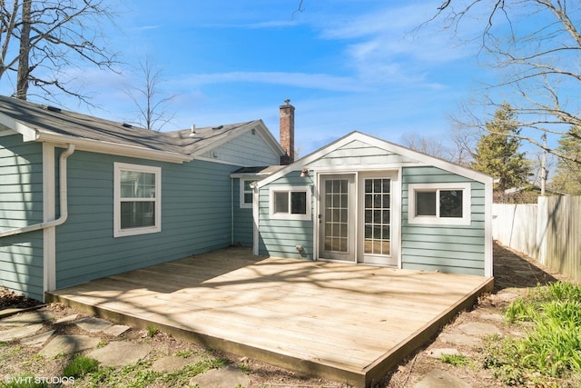rear view of property with a chimney, fence, an outbuilding, and a deck