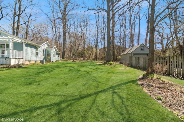 view of yard with fence, an outbuilding, and cooling unit