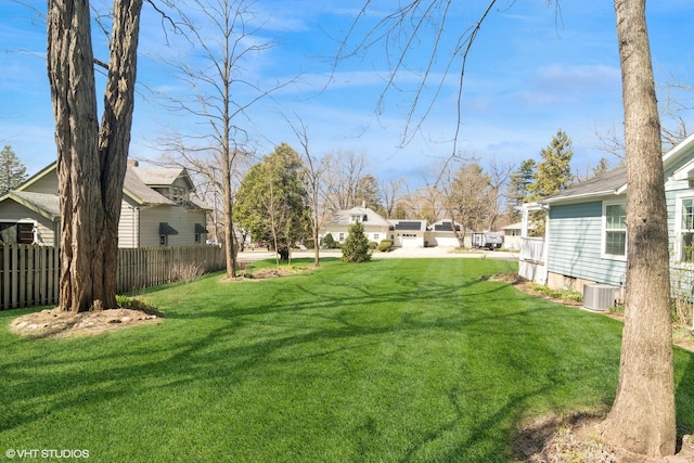 view of yard with central AC unit, fence, and a residential view