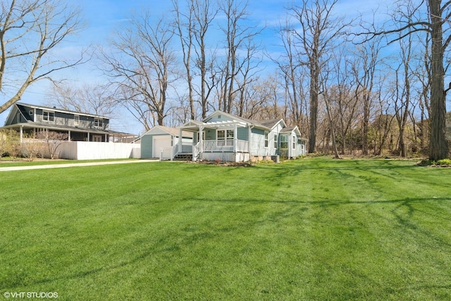 view of yard featuring fence, an outbuilding, and a porch