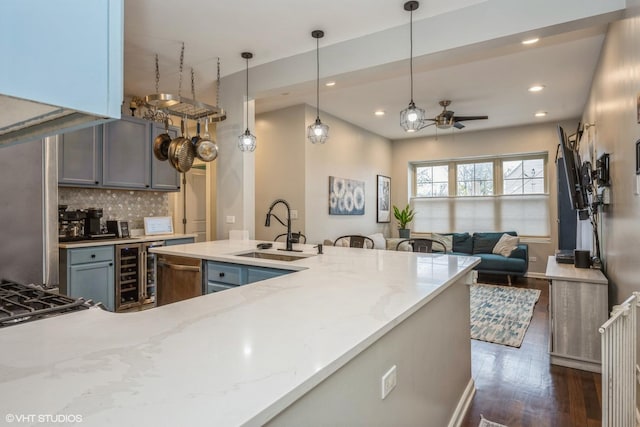 kitchen featuring a sink, beverage cooler, a ceiling fan, tasteful backsplash, and dark wood-type flooring