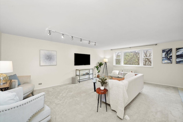 living room featuring baseboards, rail lighting, and light carpet