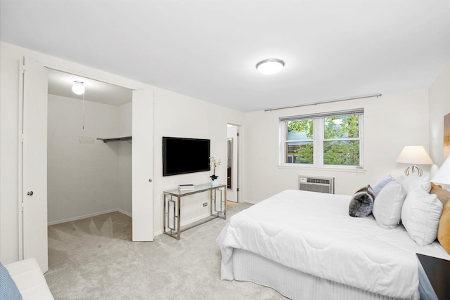 carpeted bedroom featuring an AC wall unit, baseboards, and a walk in closet