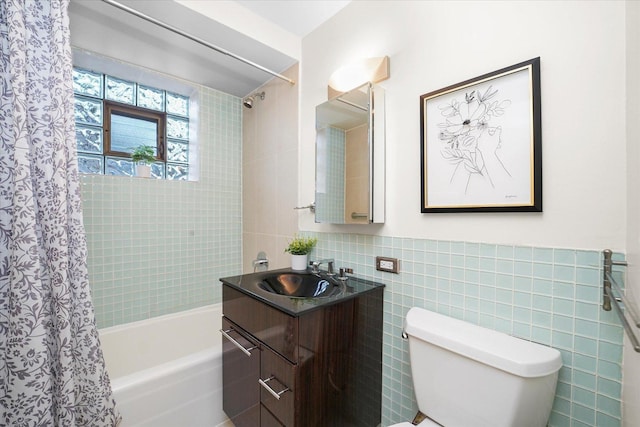 full bath with tile walls, shower / bath combo with shower curtain, vanity, and toilet
