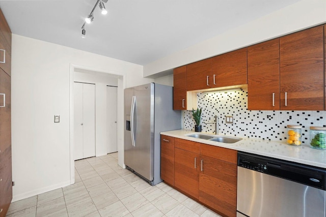 kitchen featuring light countertops, appliances with stainless steel finishes, a sink, and tasteful backsplash