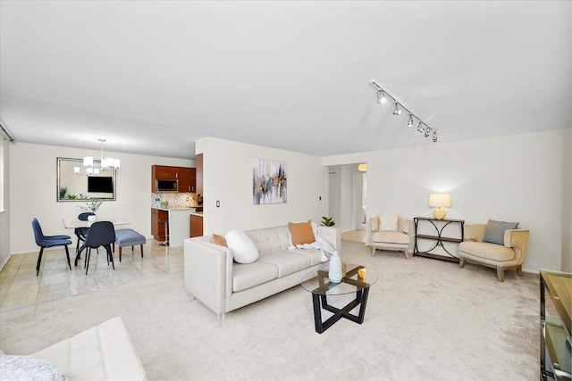 living area featuring an inviting chandelier, track lighting, and light carpet