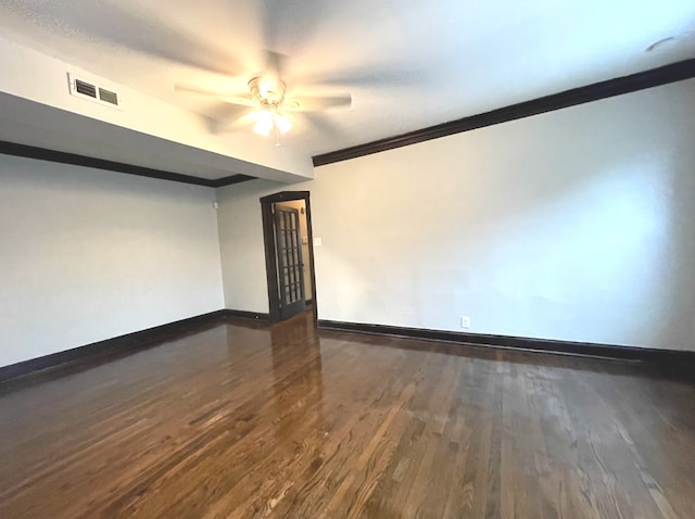 empty room with baseboards, ornamental molding, wood finished floors, and visible vents