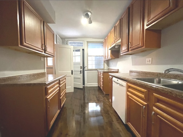 kitchen featuring brown cabinetry, dark wood-style flooring, dark countertops, dishwasher, and a sink