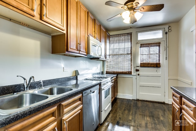 kitchen with gas range, stainless steel dishwasher, a sink, white microwave, and dark wood-style floors