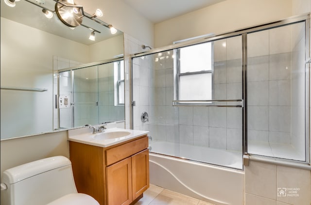 bathroom featuring vanity, combined bath / shower with glass door, tile patterned floors, and toilet