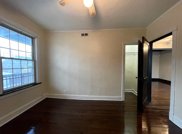 empty room with crown molding, baseboards, visible vents, and dark wood-type flooring