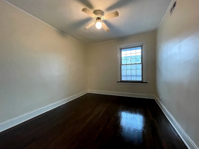 spare room with baseboards, ornamental molding, a ceiling fan, and dark wood finished floors