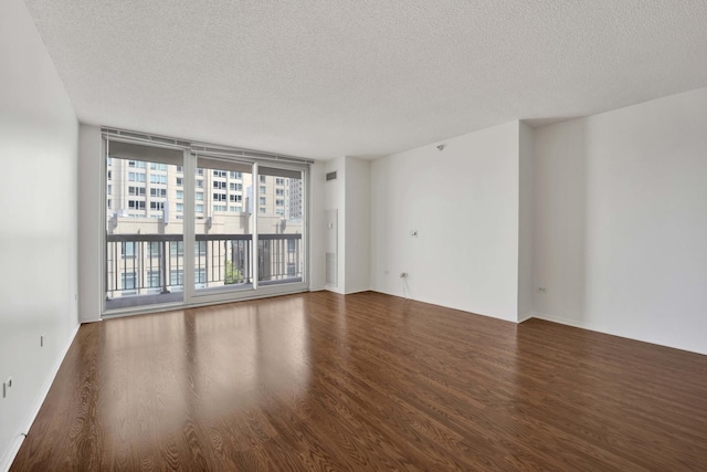 empty room featuring wood finished floors, a textured ceiling, and baseboards