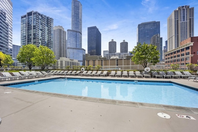 community pool featuring a skyline view and fence