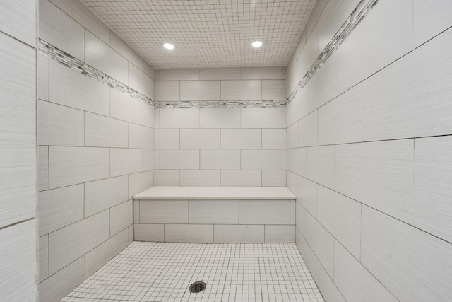 full bathroom featuring a tile shower, recessed lighting, and tile walls