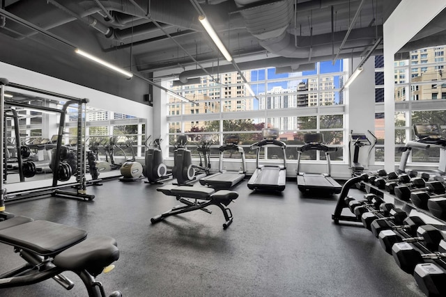 exercise room with a city view and a high ceiling