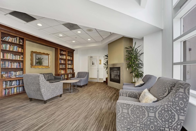 sitting room with a glass covered fireplace, built in features, and a drop ceiling