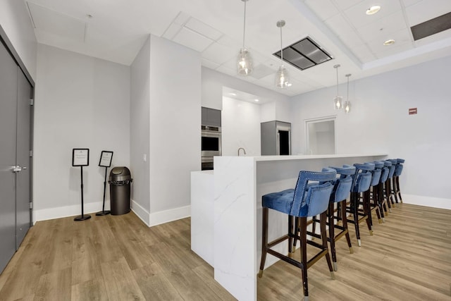 kitchen featuring light wood-style floors, a kitchen bar, baseboards, and modern cabinets