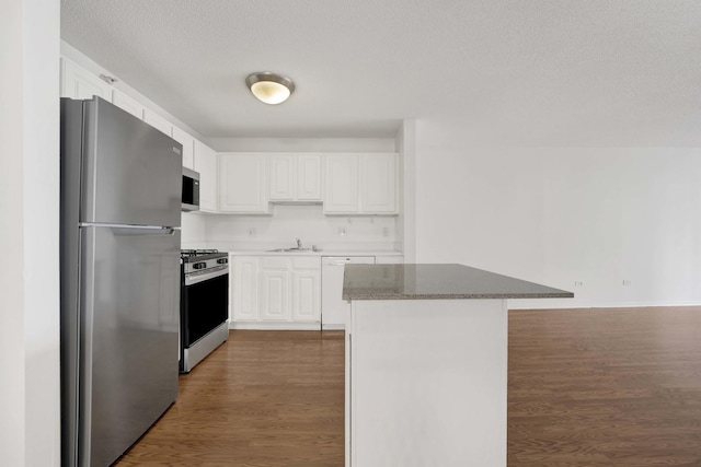 kitchen featuring appliances with stainless steel finishes, dark wood-type flooring, white cabinetry, a sink, and a textured ceiling