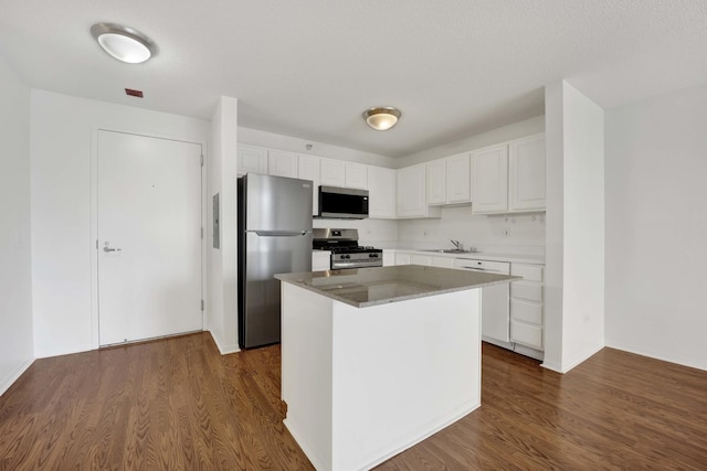 kitchen with appliances with stainless steel finishes, a sink, white cabinetry, and dark wood finished floors