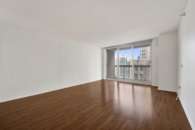 unfurnished room with wood finished floors, a textured ceiling, baseboards, and floor to ceiling windows
