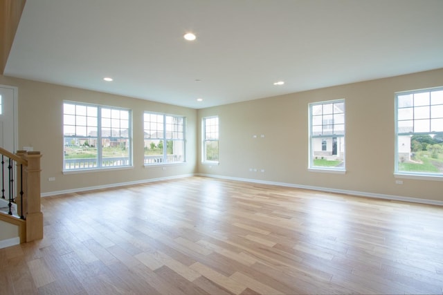 unfurnished living room featuring stairway, baseboards, recessed lighting, and light wood finished floors
