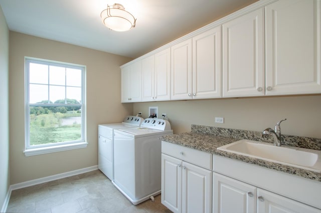 clothes washing area with cabinet space, baseboards, washing machine and dryer, and a sink